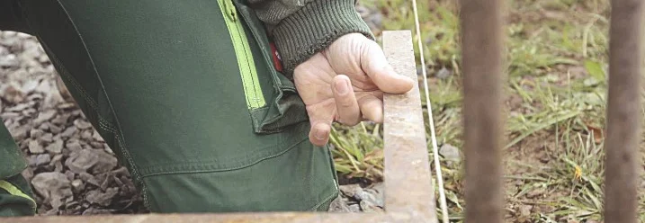 Person richtet Holzbalken mit Wasserwaage aus